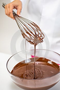 Melted chocolate pouring from whisk chocolatier makes luxurious handmade candies photo