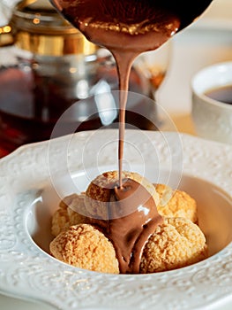 Melted chocolate pours onto profiteroles