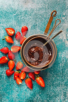 Melted dark chocolate in copper pot  and strawberry pieces