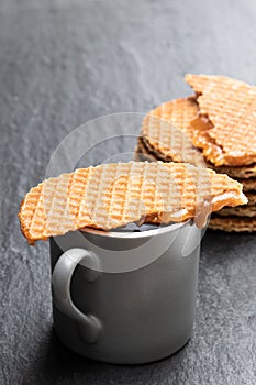 Melted Dutch caramel waffles with cup of coffee on black stone background