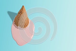 Melted ice cream with ice cream cone on pastel blue background. Minimal summer food concept