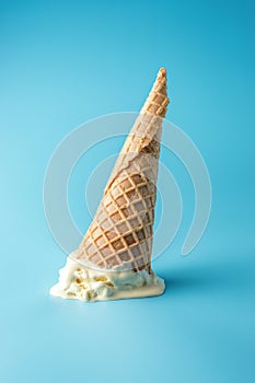 Melted ice cream with ice cream cone on pastel blue background. Minimal summer food concept