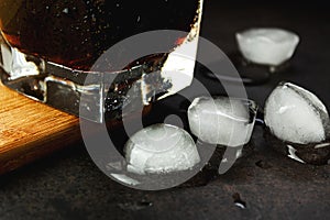 Melted ice on a dark background near a glass in a close-up