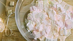 Melted marshmallows in a clear bowl. Christmas atmosphere with lights in the background. Slider shooting