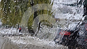 Melted snow and rain drops on the windshield of a car. Blurred outdoor view, winter season sleet as seen out of vehicle window