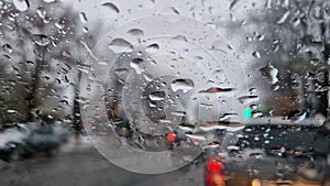 Melted snow and rain drops on the windshield of a car. Blurred outdoor view, winter season sleet as seen out of vehicle window