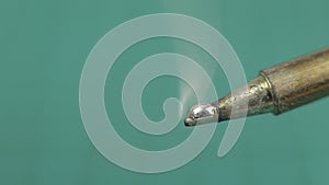 Melted solder wire over a hot soldering iron tip. Extreme close up.