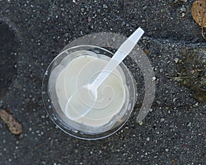 Melted Vanilla Ice Cream Cup and Spoon on Asphalt
