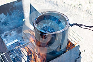 Melting black tar over a fire in a can of smoke