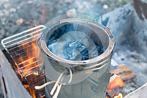 Melting black tar over fire in can of smoke