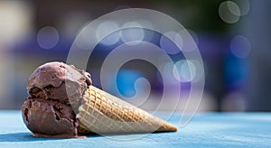 Melting Chocolate Ice Cream in Waffle Cone on Blue Surface