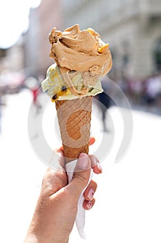 Melting delicious ice cream in waffle cone gelato pistachio salty caramel holding female hand