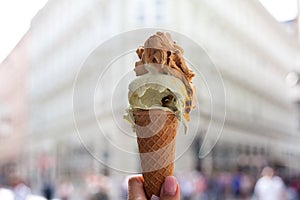 Melting delicious ice cream in waffle cone gelato pistachio salty caramel holding female hand