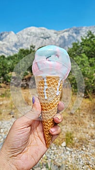 Melting gelato ice cream cone held up to the hot summer day