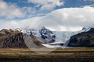 Melting glacier in Iceland surrounded by green rocky hills