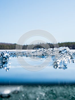 Melting ice crystals on surface of clear-watered lake