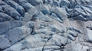 Melting ice and snow of a glacier on a rock in Norway. Close-up aerial shot, UHD