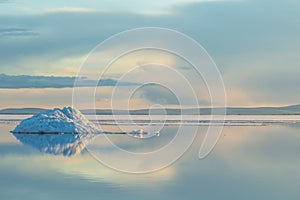 The melting iceberg on spring mountain lake in the setting sun.