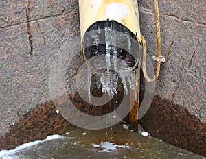 Melting icicles in a yellow downpipe