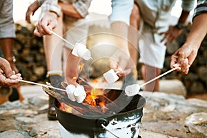 Melting marshmallows by a fire on a nature getaway vacation, group bonding and relaxing together outside with candy in