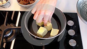 Melting and mixing a piece of butter in a saucepan on the gas stove, butter becoming liquid.