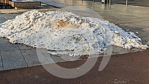 Melting pile of snow on the city pavement