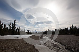 Melting snow and water in gravel riverbed under lenticular clouds in the spring in Denali National Park in Alaska USA