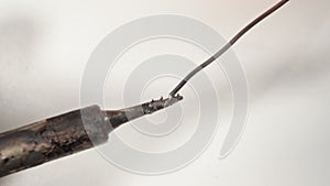 Melting solder with a soldering iron on a white background. Macro.