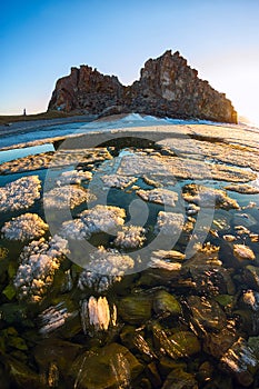 Melting spring ice of Lake Baikal, on the rock Shamanka at sunset