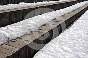 Melting on spring snow on the old brown wooden boards outdoors side view closeup