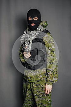 A member of the special police squad, takes aim, holds a pistol. Dressed in a balaclava,  camouflage uniform, bulletproof vest.
