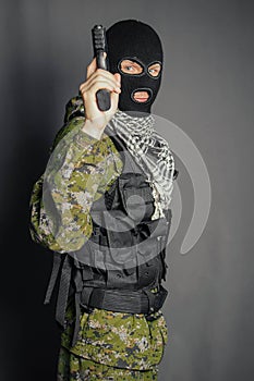 A member of the special police squad, takes aim, holds a pistol. Dressed in a balaclava,  camouflage uniform, bulletproof vest.