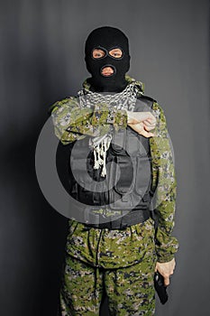 A member of the special police squad, takes aim, holds a pistol. Dressed in a balaclava,  camouflage uniform, bulletproof vest.