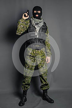 A member of the special police squad, takes aim, holds a pistol. Dressed in a balaclava,  camouflage uniform, bulletproof vest.