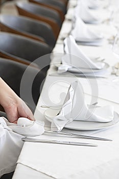 Member of staff meticulously polishing the silverware in preparation for a formal dinner