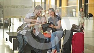 Members of a big family are watching photos from the vacation in tablet PC while sitting in waiting room of airport or