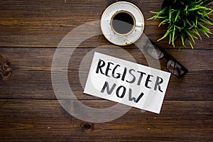Membership concept. Template for registration. Register now hand lettering iconon word desk with glasses, coffee, plant