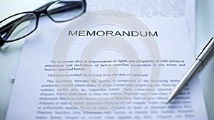 Memorandum lying on table, pen and eyeglasses on official document, business