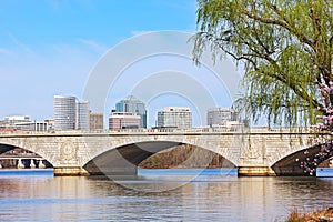 The Memorial Bridge over Potomac River and a city skyline during cherry blossom in Washington DC.