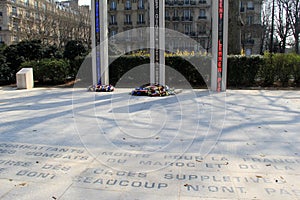 Memorial outside The Eiffel Tower, with flowers placed beneath tall columns,Paris,France,2016