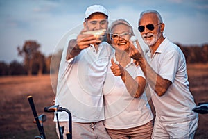 Memories on the court. Senior golfers using phone and taking self portrait. Focus is on background