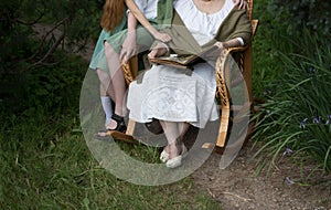 Memories of the elderly. grandmother with her grandchildren sitting in a rocking chair in the garden and watching an old album wit