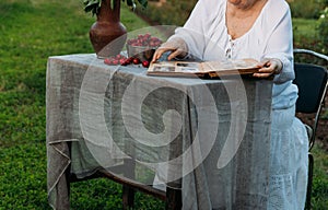 Memories of the elderly. visit grandmother. grandmother sitting in a chair in the garden and watching an old album with photos, re