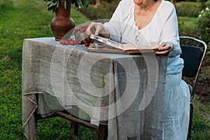 Memories of the elderly. visit grandmother. grandmother sitting in a chair in the garden and watching an old album with photos, re