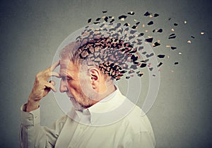 Memory loss due to dementia. Senior man losing parts of head as sign of decreased mind function.