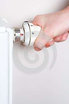 Men adjusting thermostat on home radiator