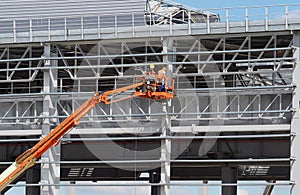 Men on aerial platform work on the frame of new building under construction.