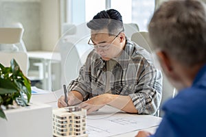 Men architects working with blueprints modeling modern house.