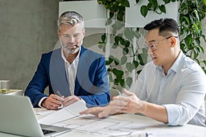 Men architects working on construction plans, engineers discussing on project in office.