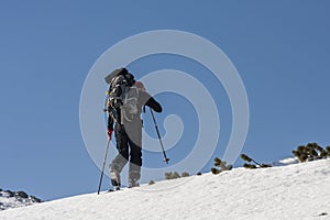 Men ascending profiled on a blue sky during ski touring